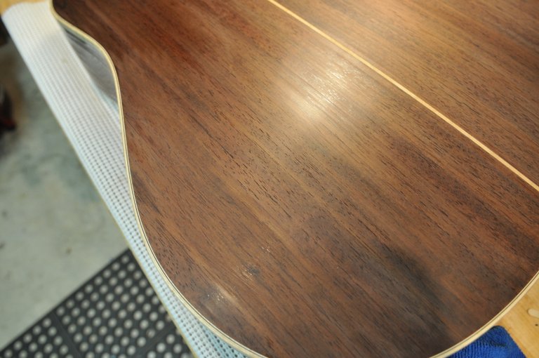 Photo taken after another coat, and more sanding.  See the uniformly dull area on the lower left of the guitar?  That section is basically done (no more shiny or dark pores there), but other areas need some more.