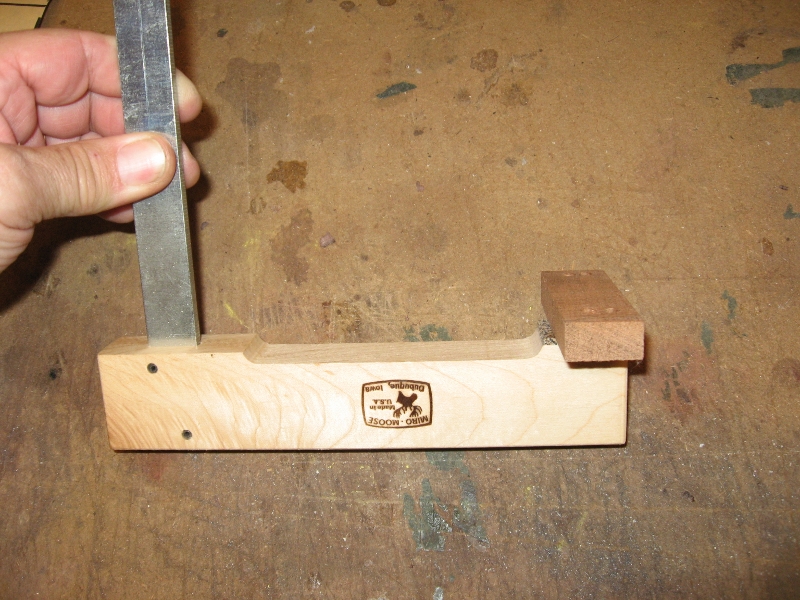 I take a piece of scrap about 1&quot; x 3&quot;, in this case a piece of mahogany and use double sided tape to stick it to a cam clamp.