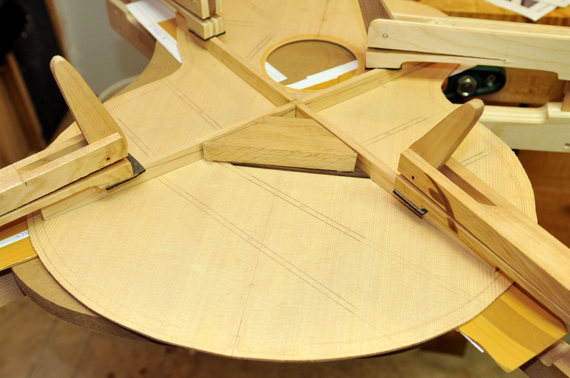 The X-brace is clamped while the bridge reinforcing piece is glued.